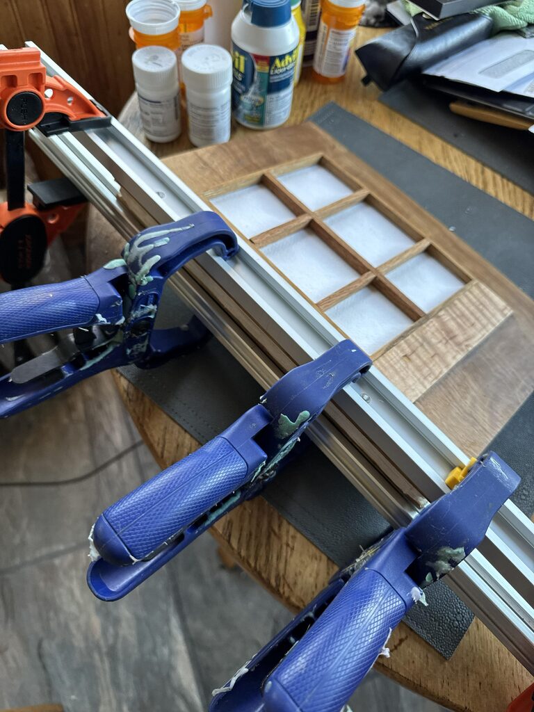 Oak logbook cover clamped during final assembly with white khadi paper visible through the wooden frame